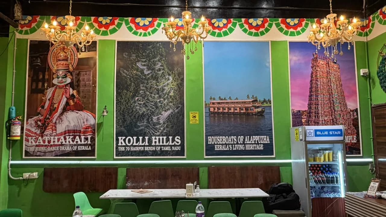 Inside the dining room: green walls, brass lamps and tables laid for service